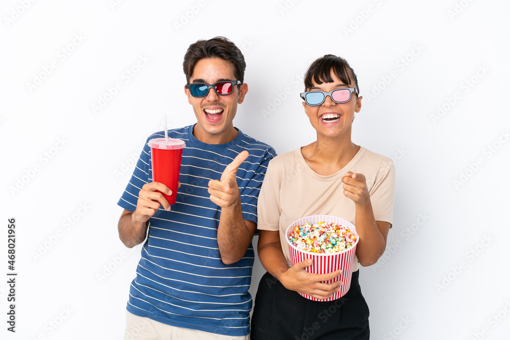 Young mixed race friends isolated on white background with 3d glasses and holding a big bucket of popcorns while pointing front