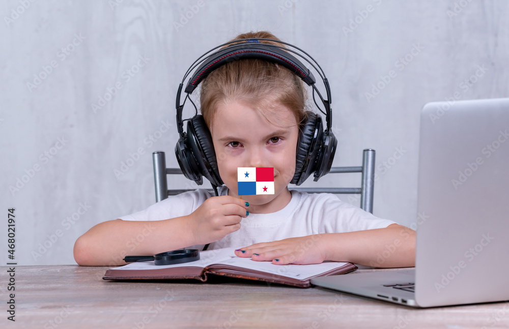 School female child with Panama flag. Child in headphones, with a book and laptop has lesson online School female child with Panama flag. Child in headphones, with a book and laptop has lesson online