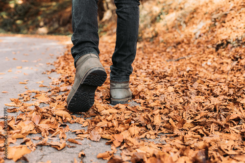 Male with winter boots walking through fallen autumn leaves