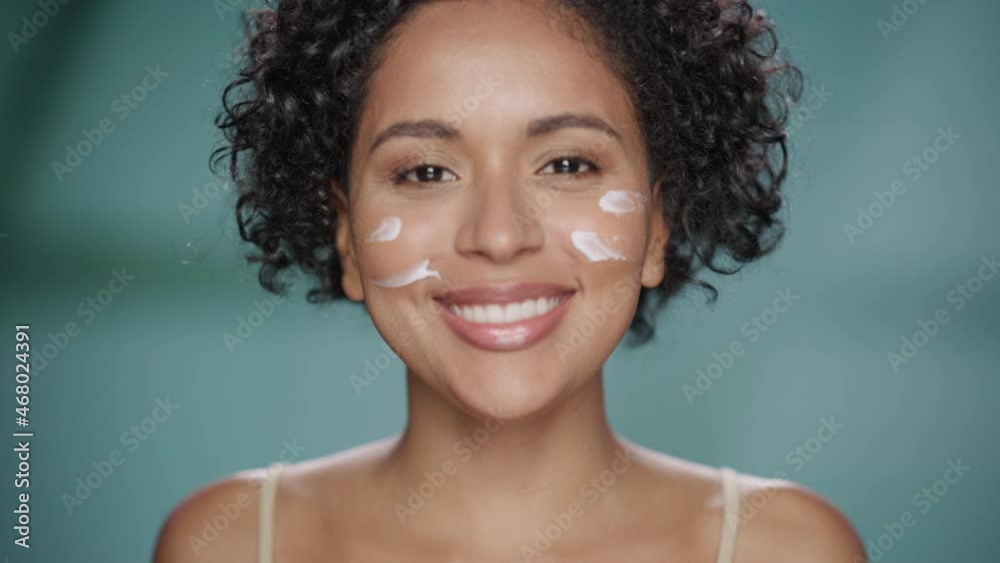 Female Beauty Portrait. Beautiful Black Woman with Afro Hair Touching Natural, Healthy Skin, Using Facial Moisturizer, Applying Face Cream. Wellness and Skincare Concept on Soft Isolated Background. Female Beauty Portrait. Beautiful Black Woman with Afro Hair Touching Natural, Healthy Skin, Using Facial Moisturizer, Applying Face Cream. Wellness and Skincare Concept on Soft Isolated Background.