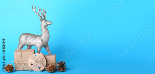 Reindeer with Christmas decor and gifts on blue background with space for text