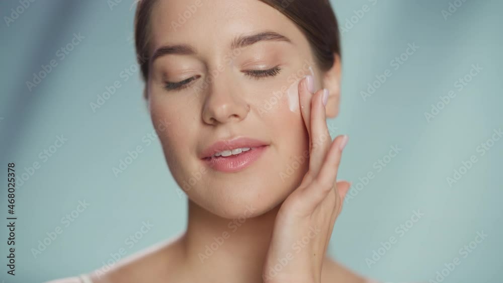 Female Beauty Portrait. Beautiful Caucasian Woman with Brown Hair Touching Natural, Healthy Skin, Using Facial Moisturizer, Applying Face Cream. Wellness and Skincare Concept on Isolated Background. Female Beauty Portrait. Beautiful Caucasian Woman with Brown Hair Touching Natural, Healthy Skin, Using Facial Moisturizer, Applying Face Cream. Wellness and Skincare Concept on Isolated Background.