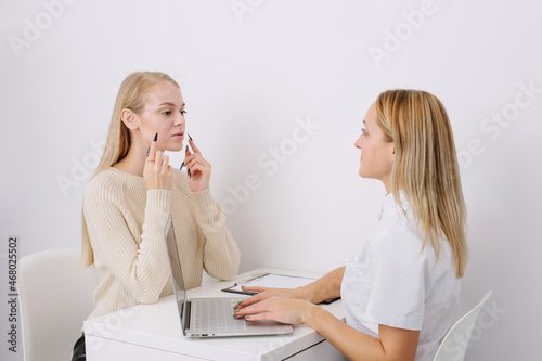 Consultation in cosmetology clinic. Female professional beauty doctor talking with pretty young female.