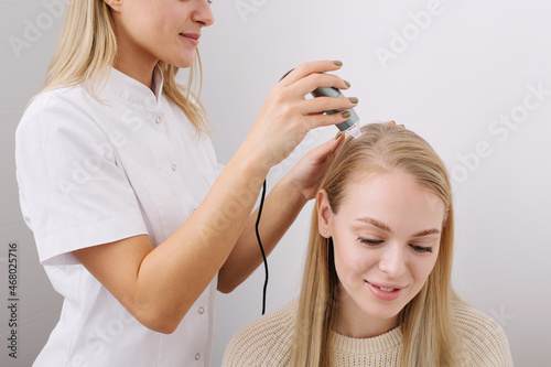 Doctor diagnoses the structure of the hair. Consultation with a trichologist