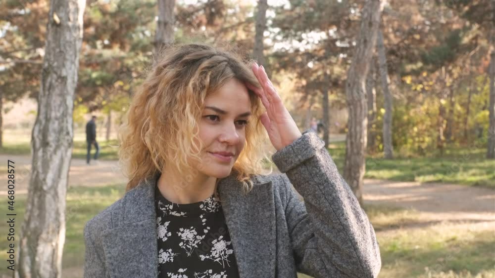 Portrait of young attractive curly woman walking in the autumn park on a sunny day Portrait of young attractive curly woman walking in the autumn park on a sunny day
