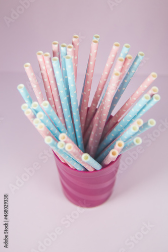 Pink and blue straws in the plastic purple cup on the pink background