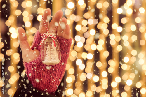 Close up of hand holding christmas ornament outdoors with snow falling