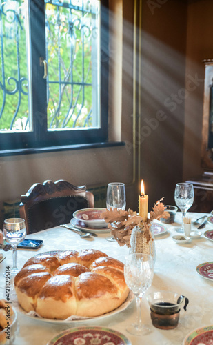 Christmas bread, candle, tree and glasses for wine.Orthodox Christmas on a table sunbathing with sunshine photo