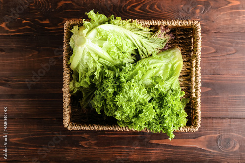 Basket with fresh lettuce on wooden background photo