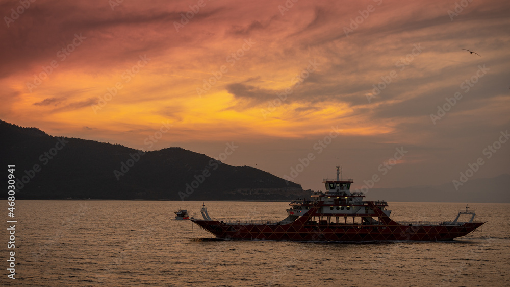Ferry boat floating on Aegean sea at sunset 
