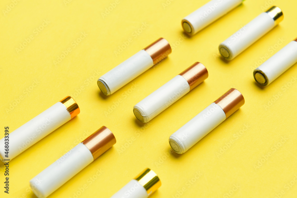Alkaline batteries in rows on yellow background Alkaline batteries in rows on yellow background