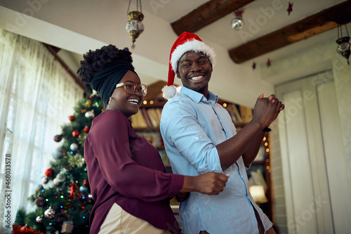 Below view of cheerful black couple dancing during Christmas day at home.