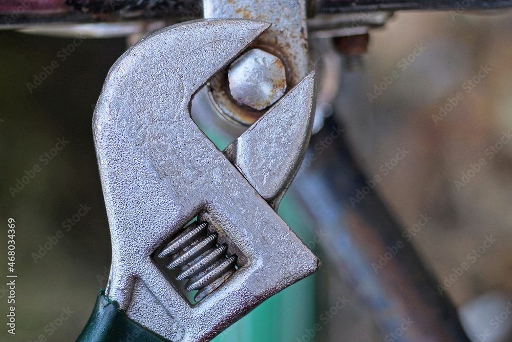 one gray adjustable wrench tightens a screw on the handlebars of an old bicycle one gray adjustable wrench tightens a screw on the handlebars of an old bicycle