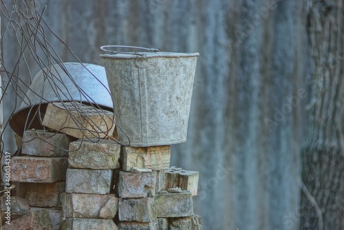 one old gray dirty metal bucket stands on a pile of bricks in the street © butus