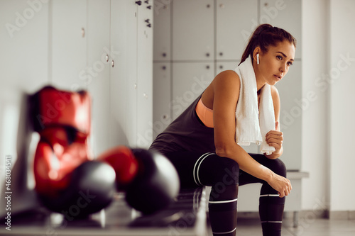Pensive female boxer sitting in locker room after sports training.