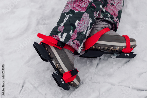 Figure skating skates. Close-up of child legs and children ice skates worn on them, snow background.  photo