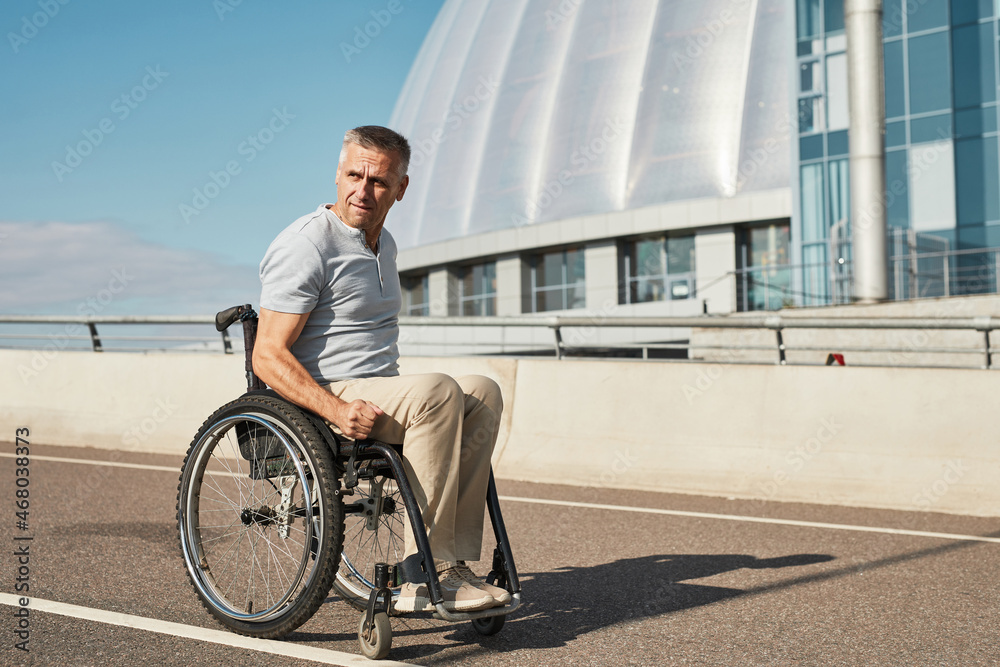 Side view portrait of adult man in wheelchair on bridge in sunlight enjoying city life, copy space Side view portrait of adult man in wheelchair on bridge in sunlight enjoying city life, copy space