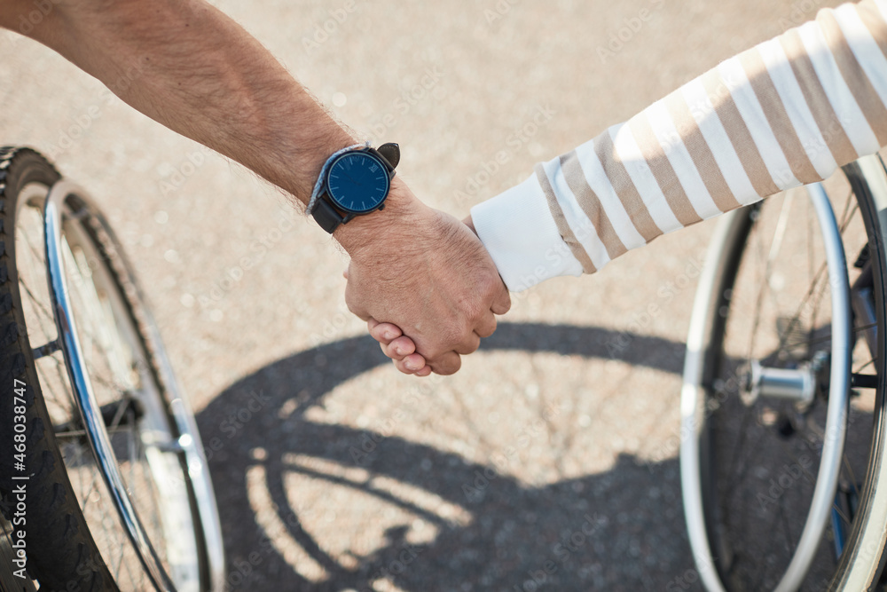 Obraz premium Close up of adult couple in wheelchairs holding hands outdoors, love and support concept, copy space