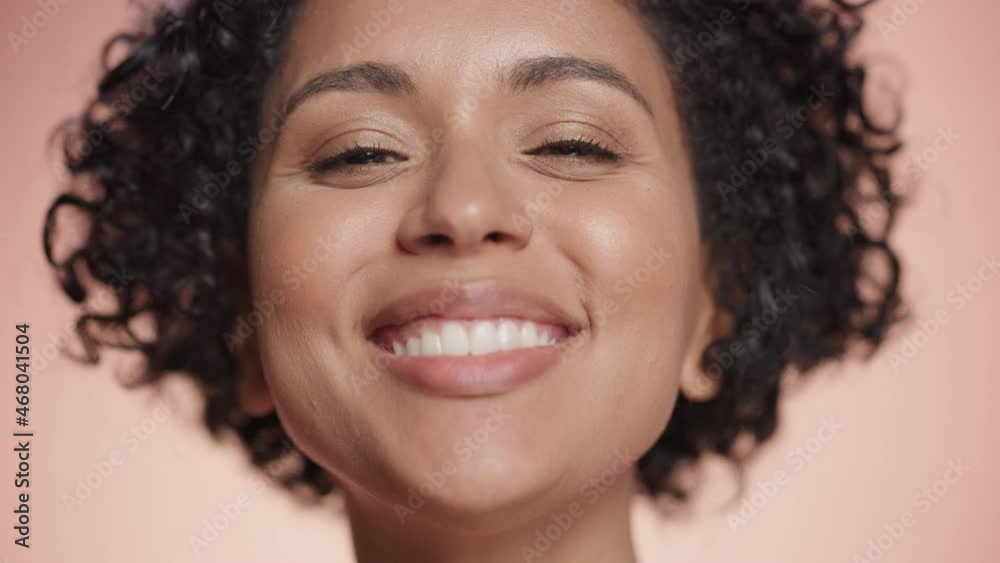 Female Beauty Portrait. Smiling Multiethnic Black Woman with Afro Hair Blowing Pink Flower Petals from Her Palms. Wellness, Health, Spa and Natural Skincare Concept on Soft Isolated Background. Female Beauty Portrait. Smiling Multiethnic Black Woman with Afro Hair Blowing Pink Flower Petals from Her Palms. Wellness, Health, Spa and Natural Skincare Concept on Soft Isolated Background.