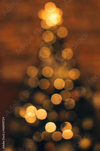 Blurred lights of a garland on a Christmas tree on a dark background.Festive Christmas and New Year background.Soft focus, copy space.