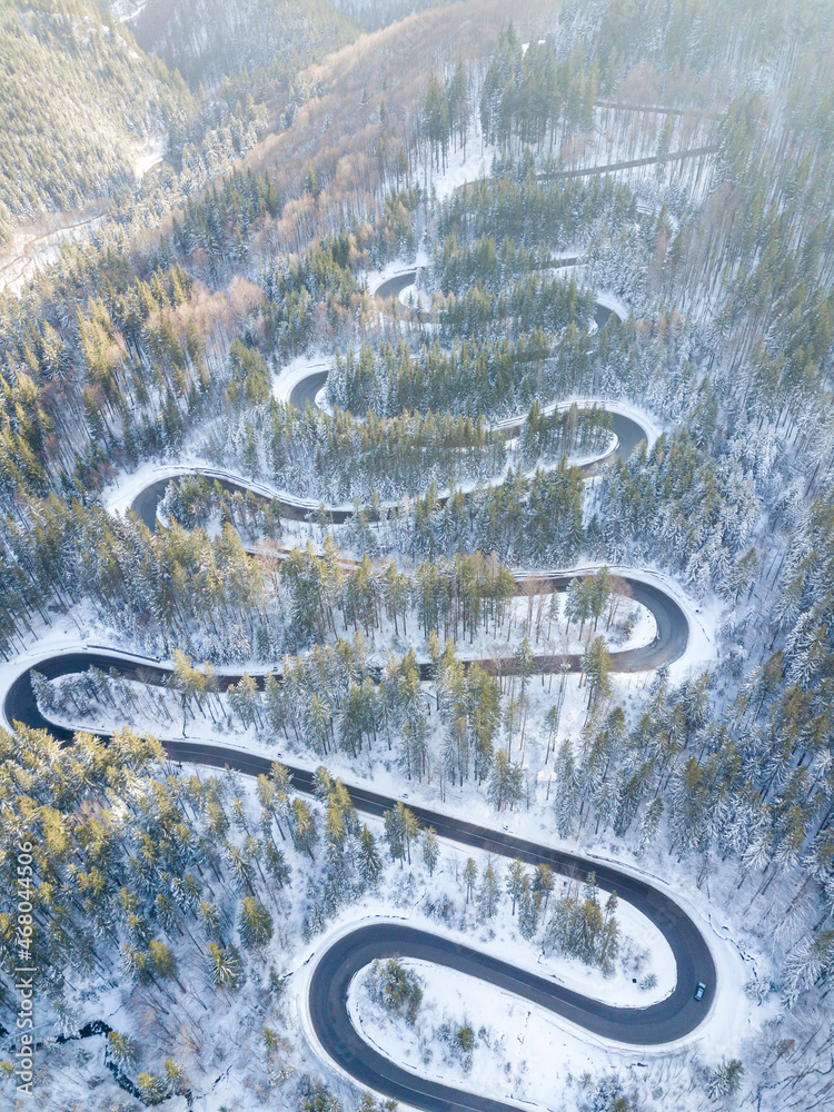 Curvy windy road in snow covered forest, top down aerial view Curvy windy road in snow covered forest, top down aerial view