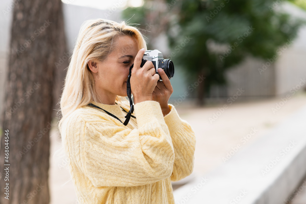Profile of a woman taking a photo with a camera in a park