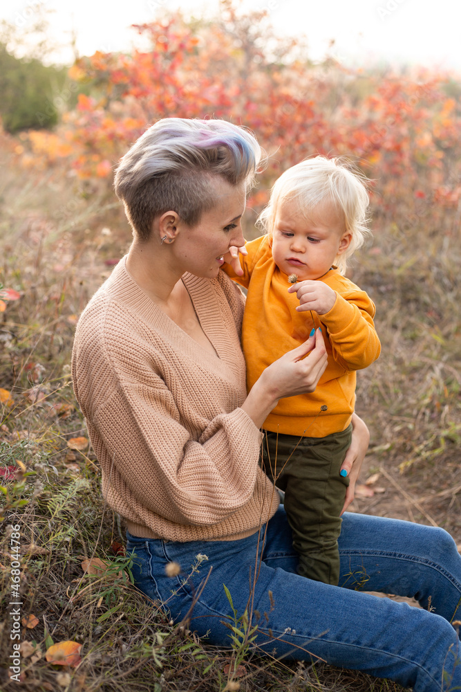 mother hugging her son in autumn background with golden and red trees mother hugging her son in autumn background with golden and red trees