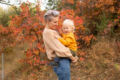 son with mother in autumn park background with golden trees