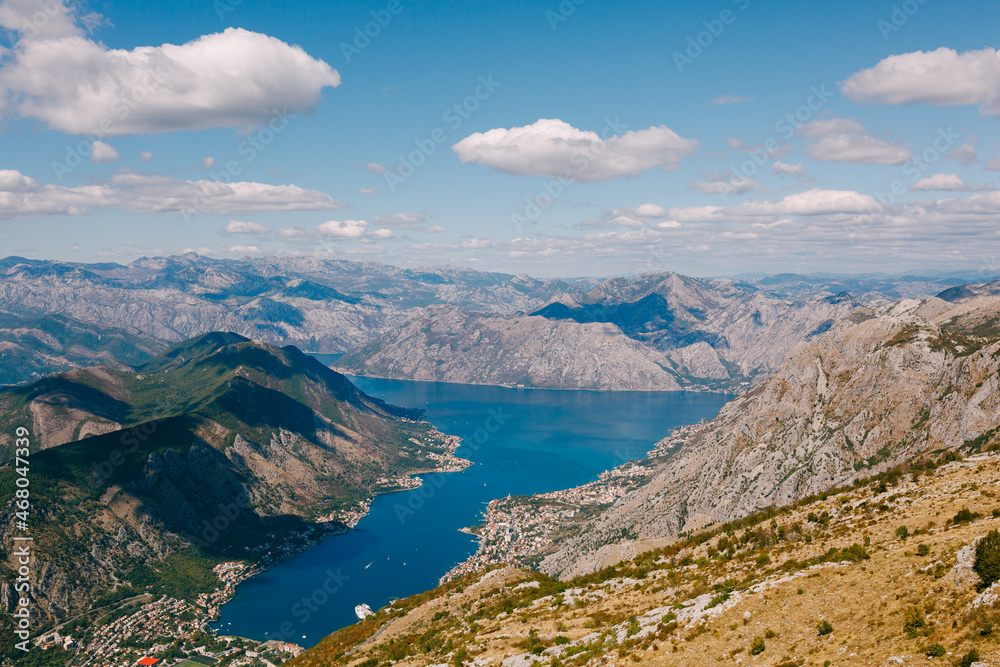 Blue sky with white clouds over the azure water of the Bay of Kotor. Mount Lovcen