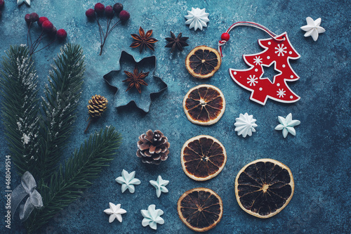 Flat lay of seasonal winter decoration, christmas tree, candies, dried oranges, berries and cones