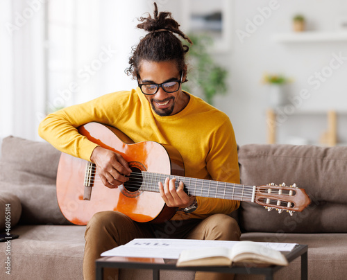 Bild auf Leinwand Focused african american male musician with classic acoustic guitar reading shee