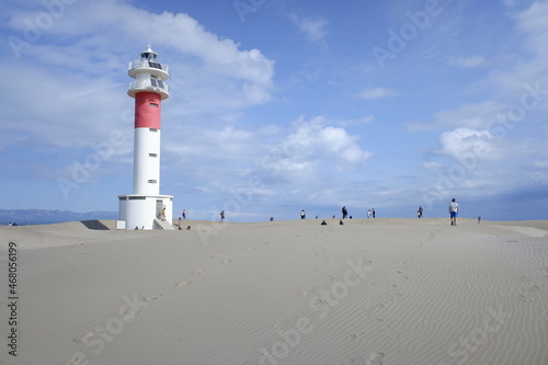 People walk on the hard sand near the Fangar beach lighthouse in the Ebro delta.