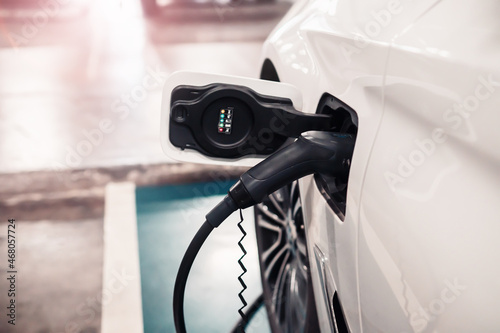 Hybrid electric car vehicle charging with pump inserted in charging socket parked waiting to be charged up. Modern technology automobile transport innovation, eco environmental energy for planet.