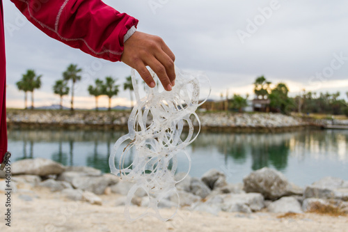 Fotografia Right hand holding six-pack cans plastic in a beach