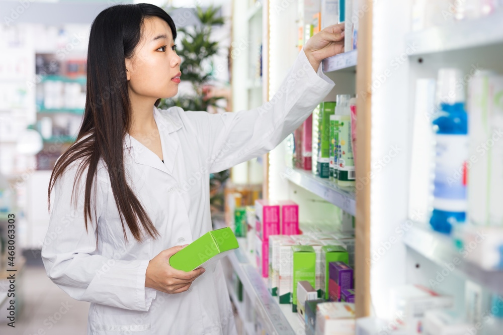 Portrait of confident female pharmacist is standing with medicines in modern drugstore