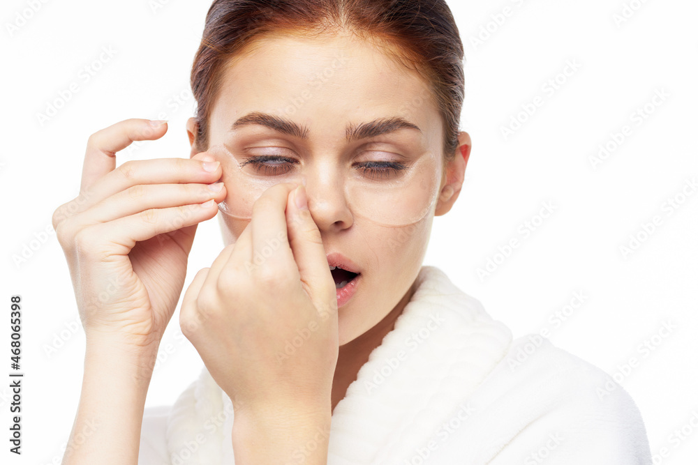 Woman in white robe posing fun skin care patches on face Woman in white robe posing fun skin care patches on face