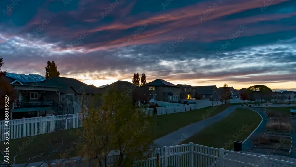 Morning sunrise over a suburban neighborhood with stunning colors as waves of clouds pass overhead - static time lapse