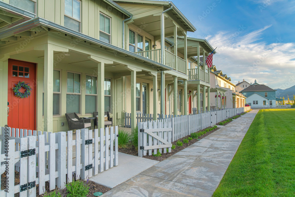 Apartment complex with light green siding and white picket fence at Daybreak, Utah