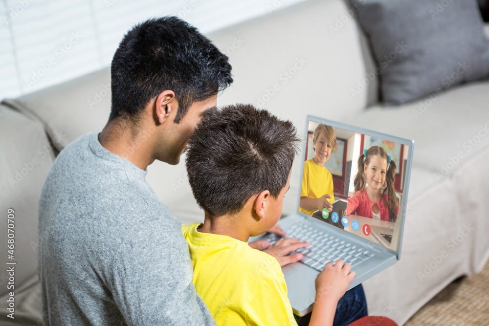 Obraz premium Biracial boy with father using laptop for video call, with elementary school pupils on screen
