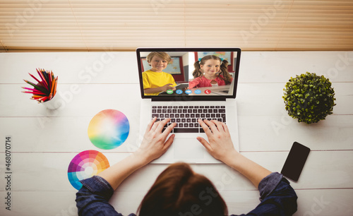 Caucasian girl using laptop for video call, with smiling elementary school pupils on screen