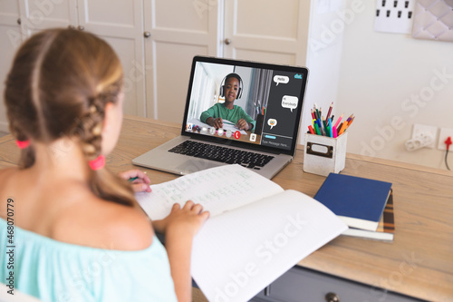 Caucasian girl using laptop for video call  with smiling elementary school pupil on screen