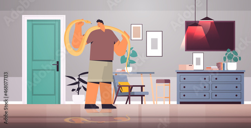 man holding yellow python snake guy having dangerous reptile pet living room interior horizontal