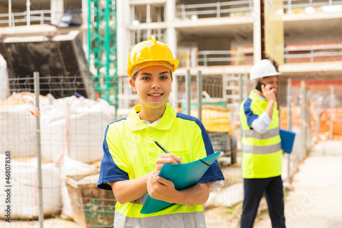 Portrait of a young confident female process engineer writing work notes on a tablet while standing on a construction site