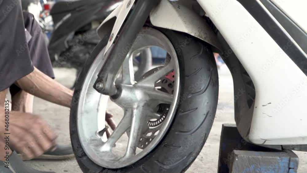 Mechanic pumping air into wheel of motorbike, static close up view Mechanic pumping air into wheel of motorbike, static close up view