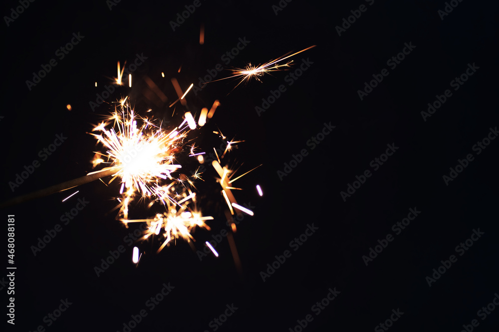 Burning sparkler on a dark background. New Years celebration concept.
