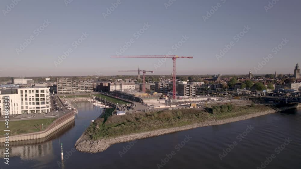 Aerial ascend and reveal of Kade Zuid apartment complex at the riverbank of river IJssel under construction between recreational port and train station in newly developed Zutphen neighbourhood Aerial ascend and reveal of Kade Zuid apartment complex at the riverbank of river IJssel under construction between recreational port and train station in newly developed Zutphen neighbourhood