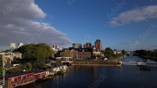 Aerial approach of Muntgebouw museum in Utrecht with small draw bridge over the canal with floating housing boats in the foreground and cloud formation in the background. Dutch urban scenery. photo