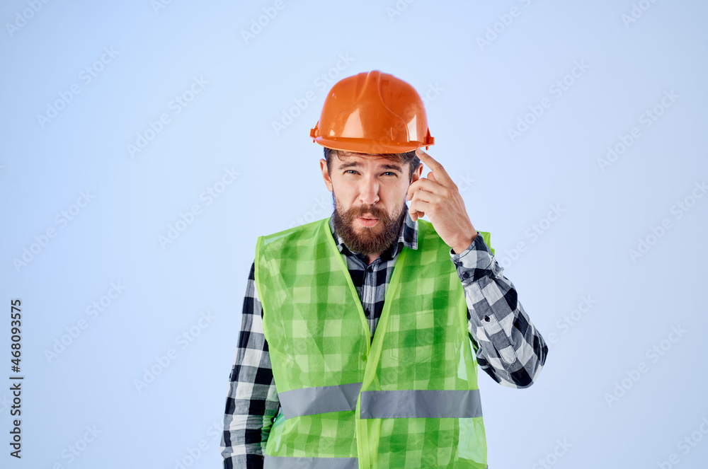 bearded man green vest orange helmet workflow hand gestures blue background