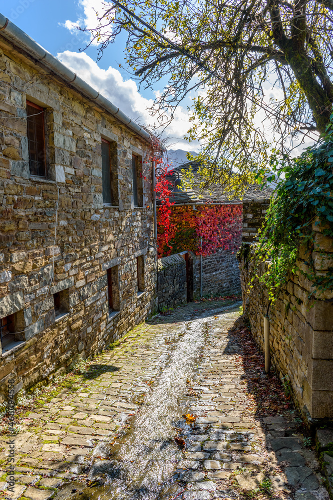 Traditional architecture  with  a narrow road and stone buildings  during  fall season in the picturesque village of papigo , zagori Greece