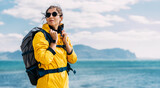 Portrait of a female traveler on the background of the sea. The concept of adventure, travel and hiking. A female tourist enjoys a beautiful landscape during a hike. Portrait of a tourist by the sea